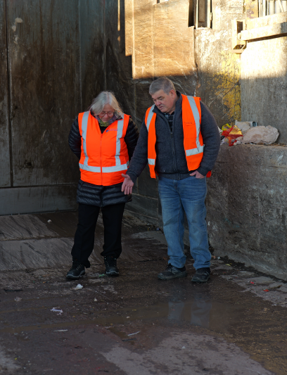 two people in hi-viz standing in an empty rubbish pit